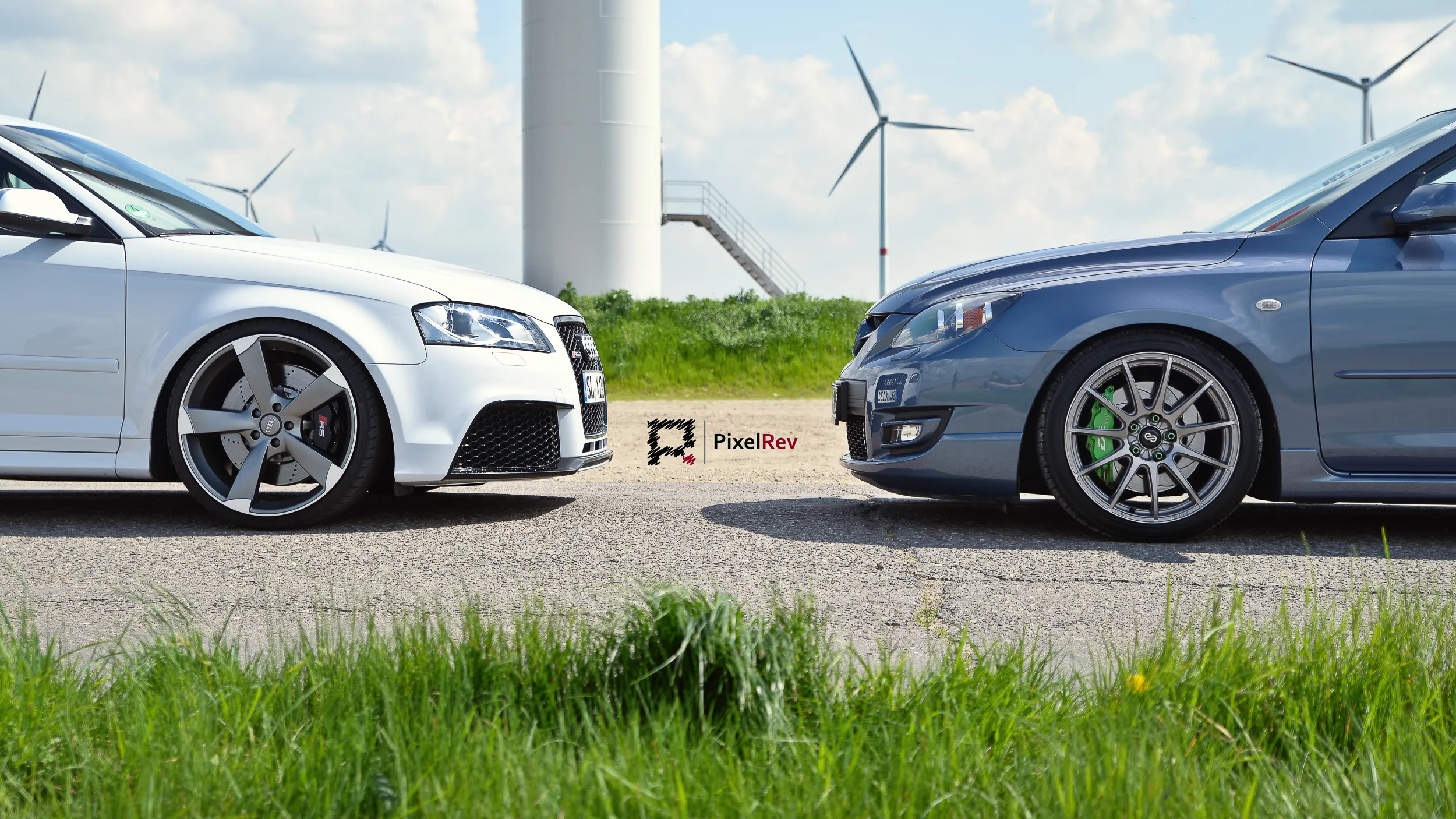 Weißer Audi RS3 und grauer Mazda 3 MPS vor einem Windrad