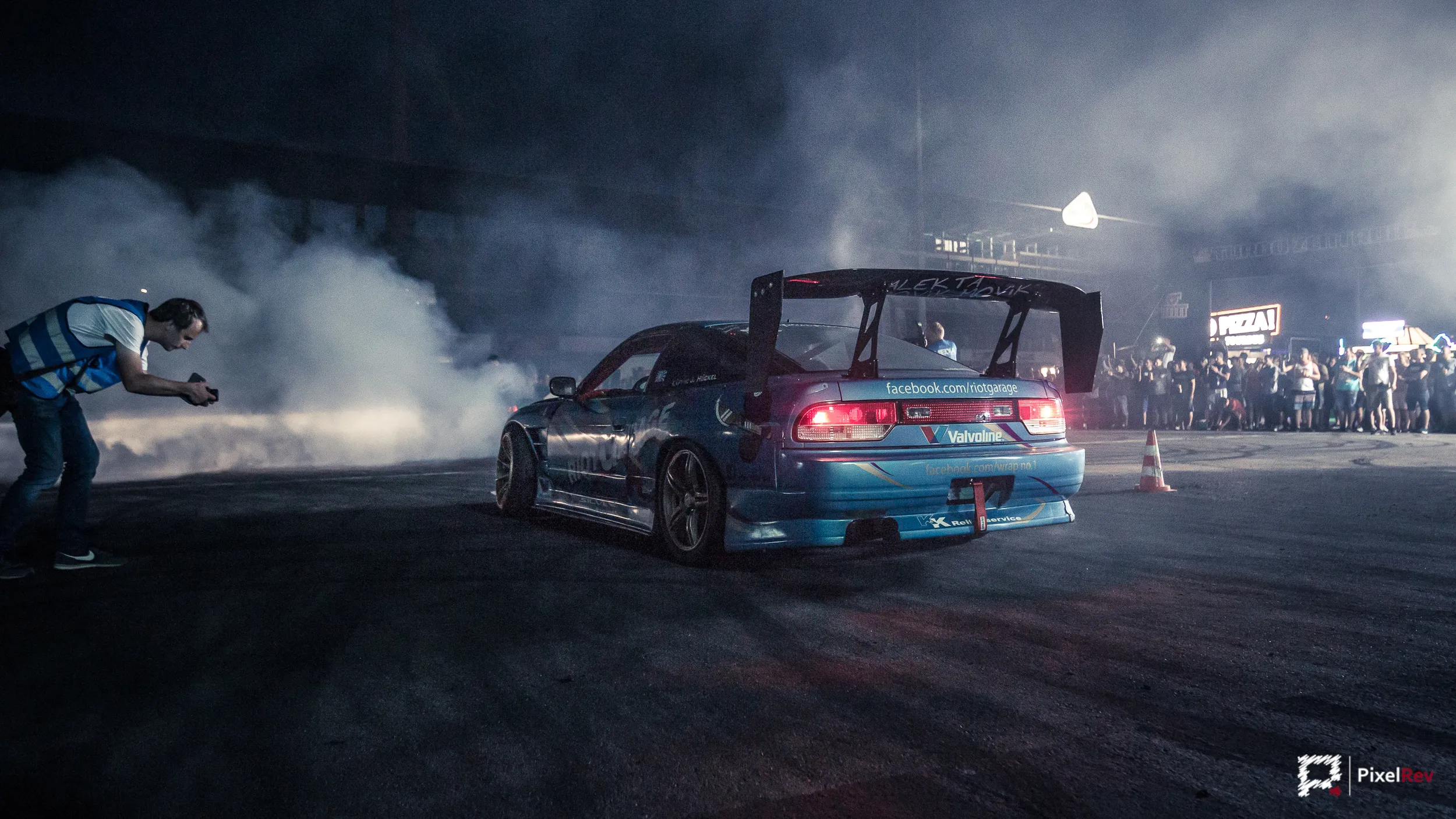 Fotograf vor einem driftenden Fahrzeug bei Nacht im Reifenqualm