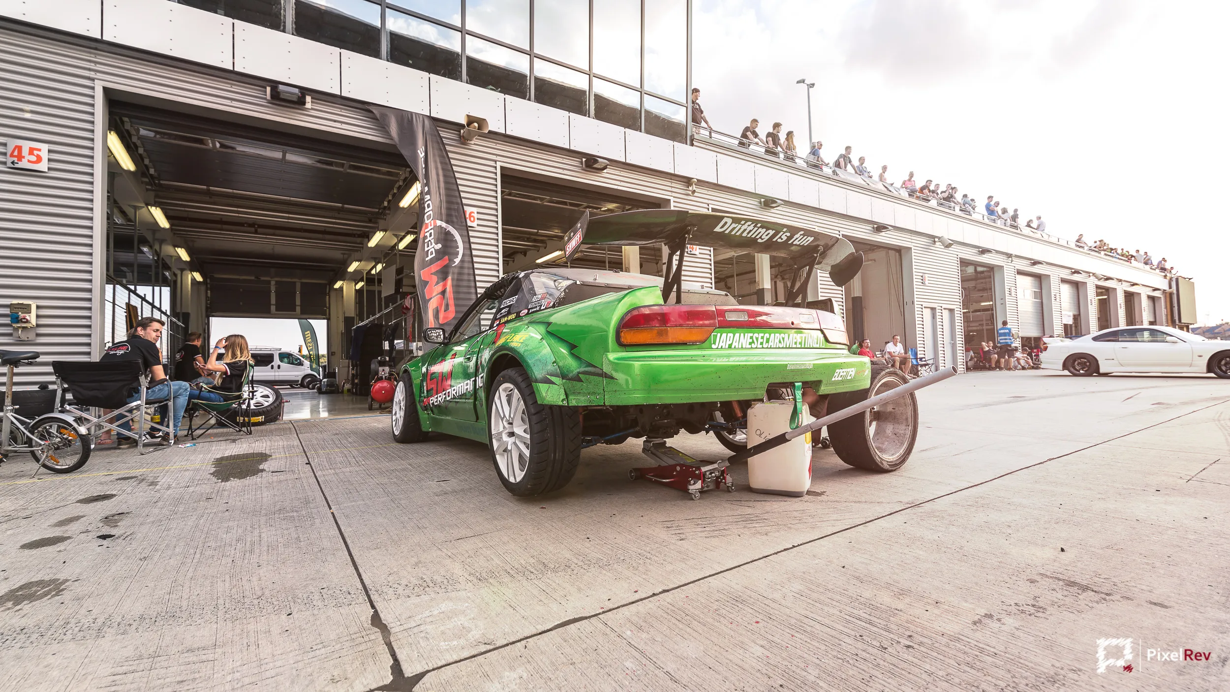 Grünes Driftfahrzeug auf dem Wagenheber vor der Box