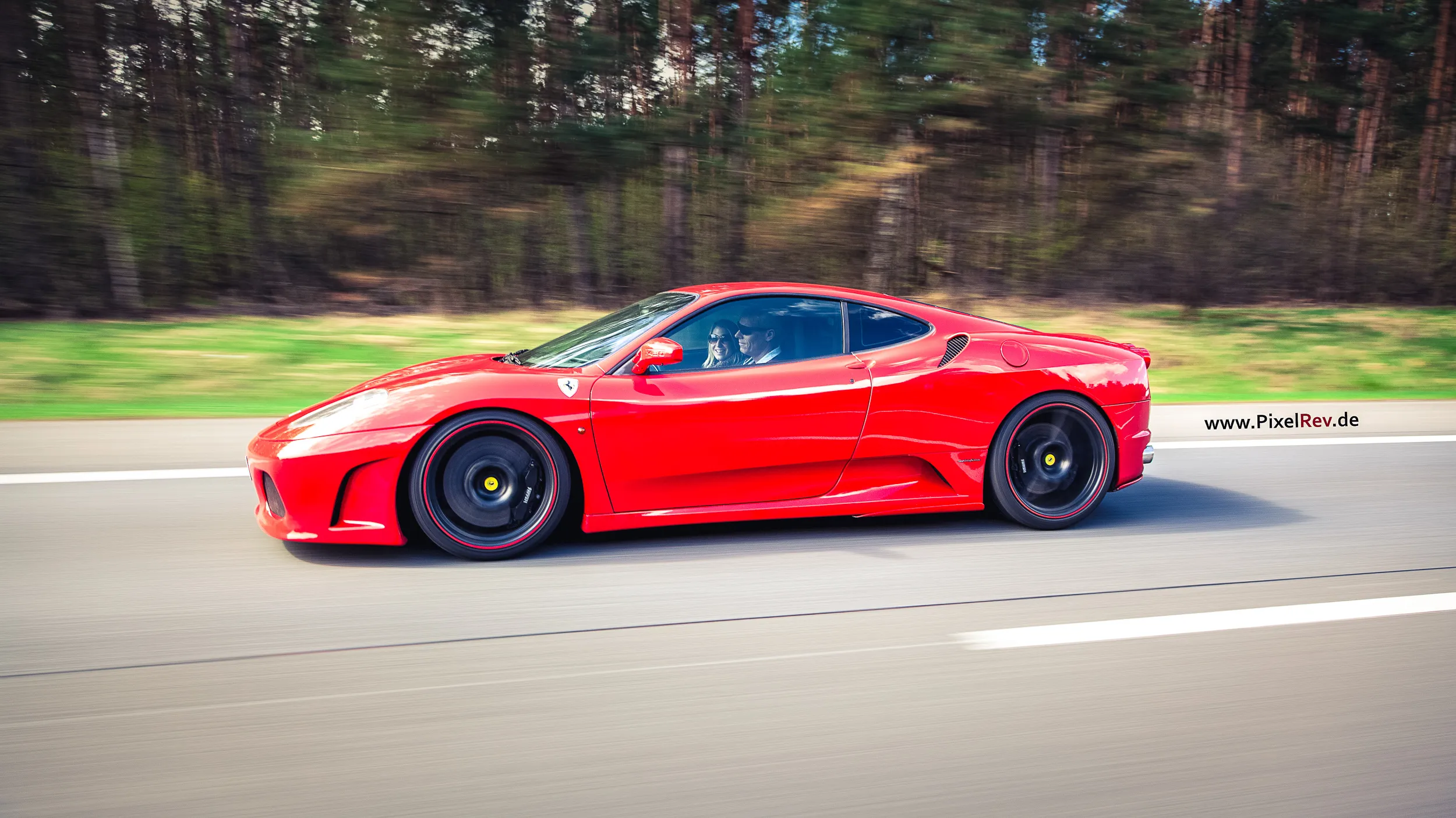 Roter Ferrari F430 in Fahrt vor verwischtem Wald bei der Saisonauftakttour 2013