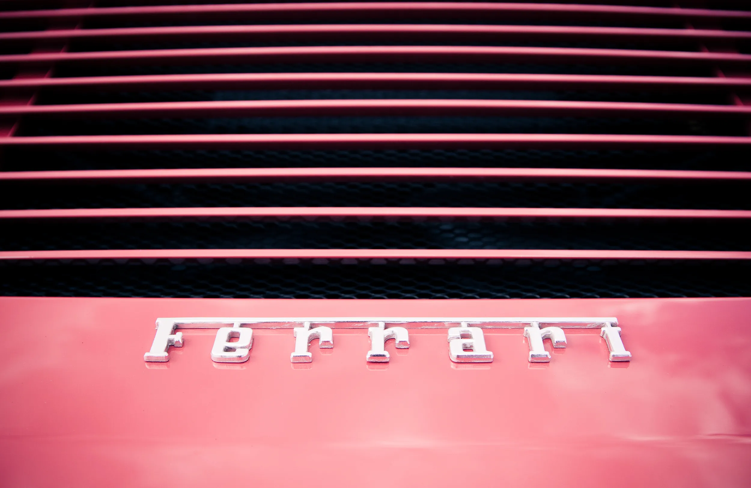 Ferrari-Schriftzug unter den Lüftungsschlitzen eines roten Ferrari, Detailaufnahme