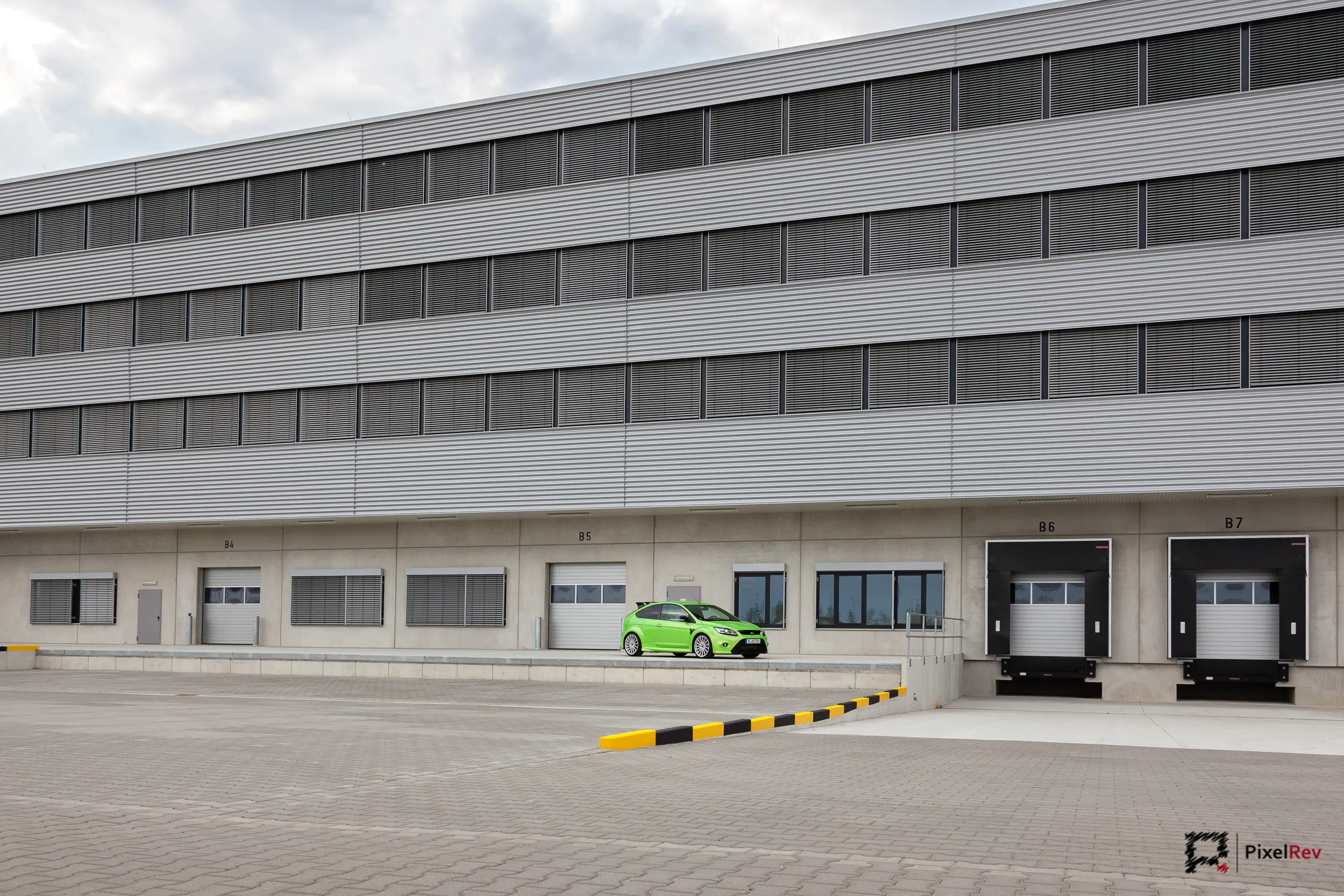 Grüner Ford Focus RS klein vor einem großen Logistikgebäude