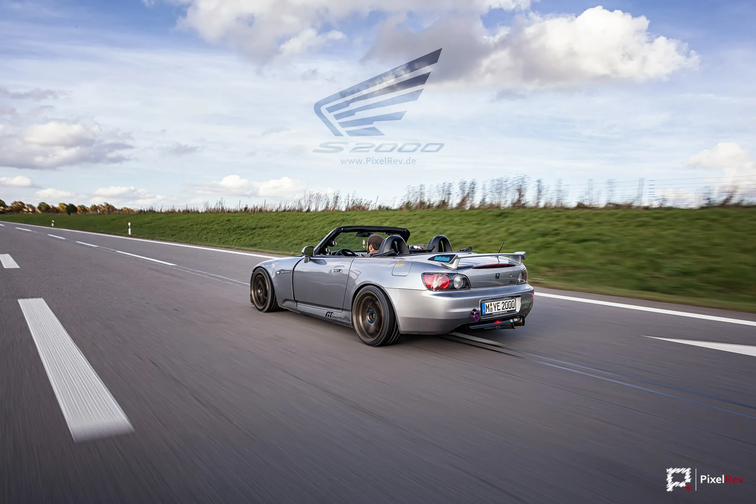Silberner Honda S2000 mit offenem Verdeck in Fahrt auf einer Landstraße bei München