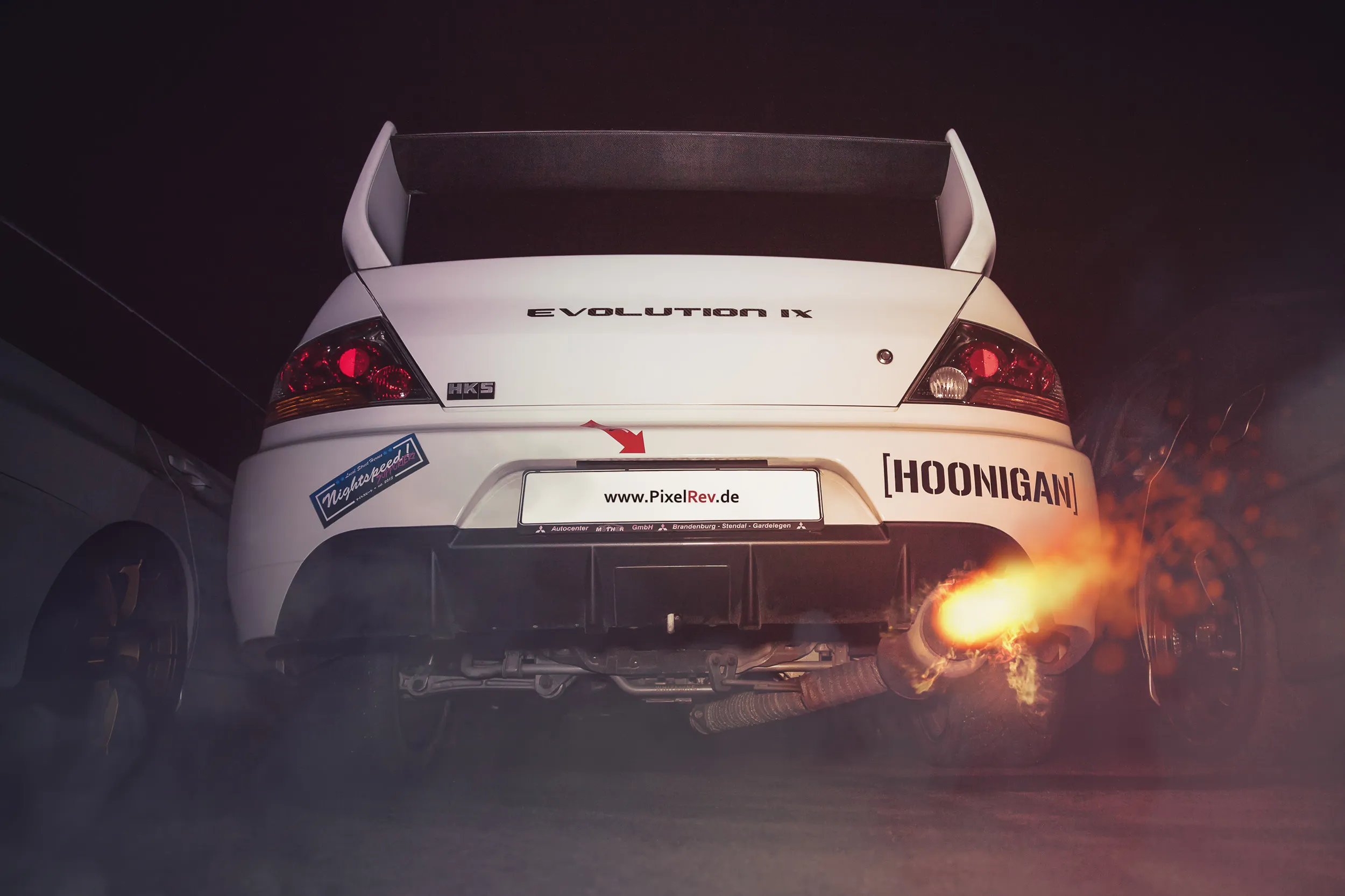 Heck eines weißen Mitsubishi Lancer Evolution IX mit Flammen aus dem Auspuff