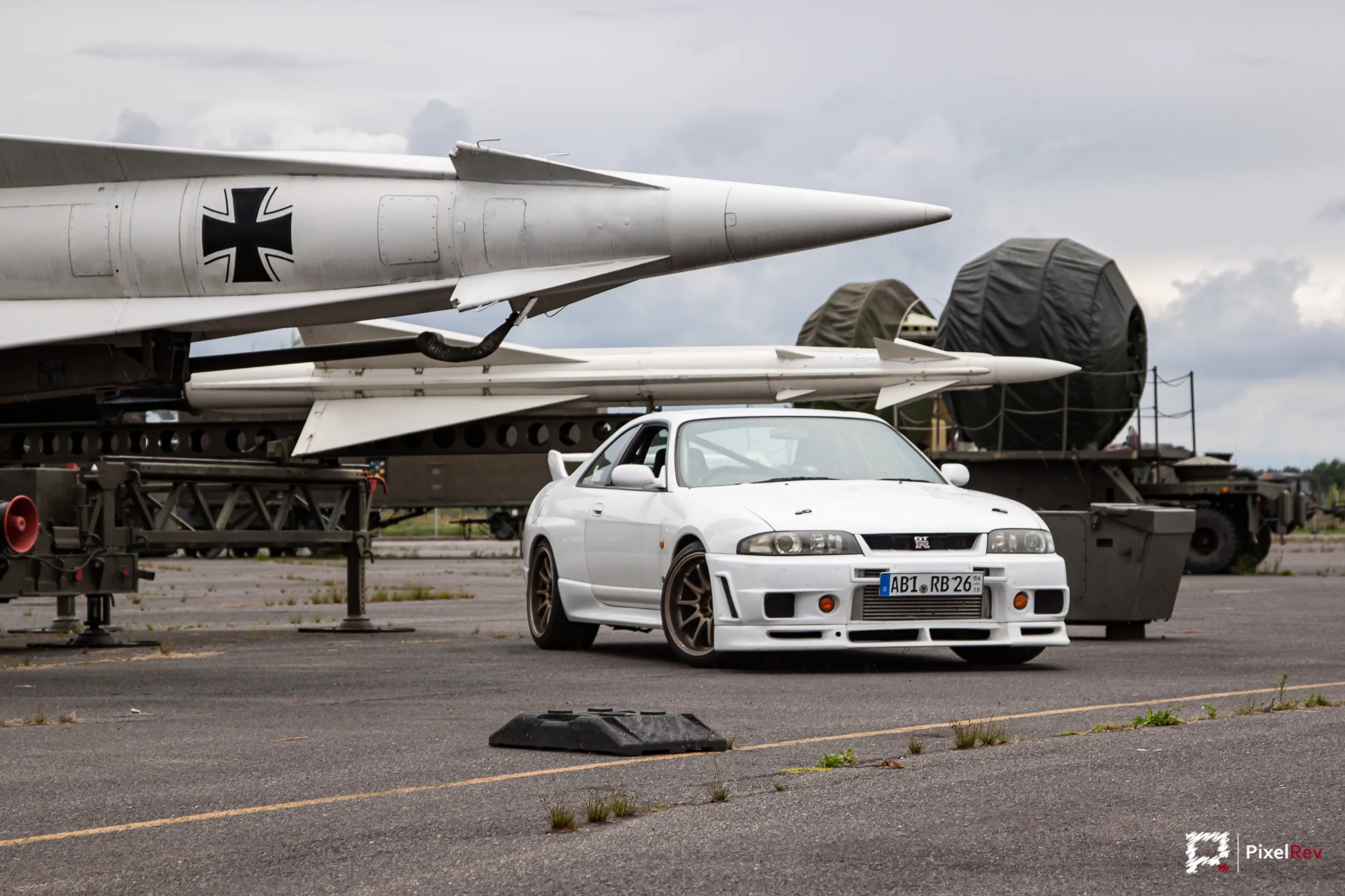 Weißer Nissan Skyline R33 GT-R vor ausgestellten Raketen im Luftwaffenmuseum Gatow