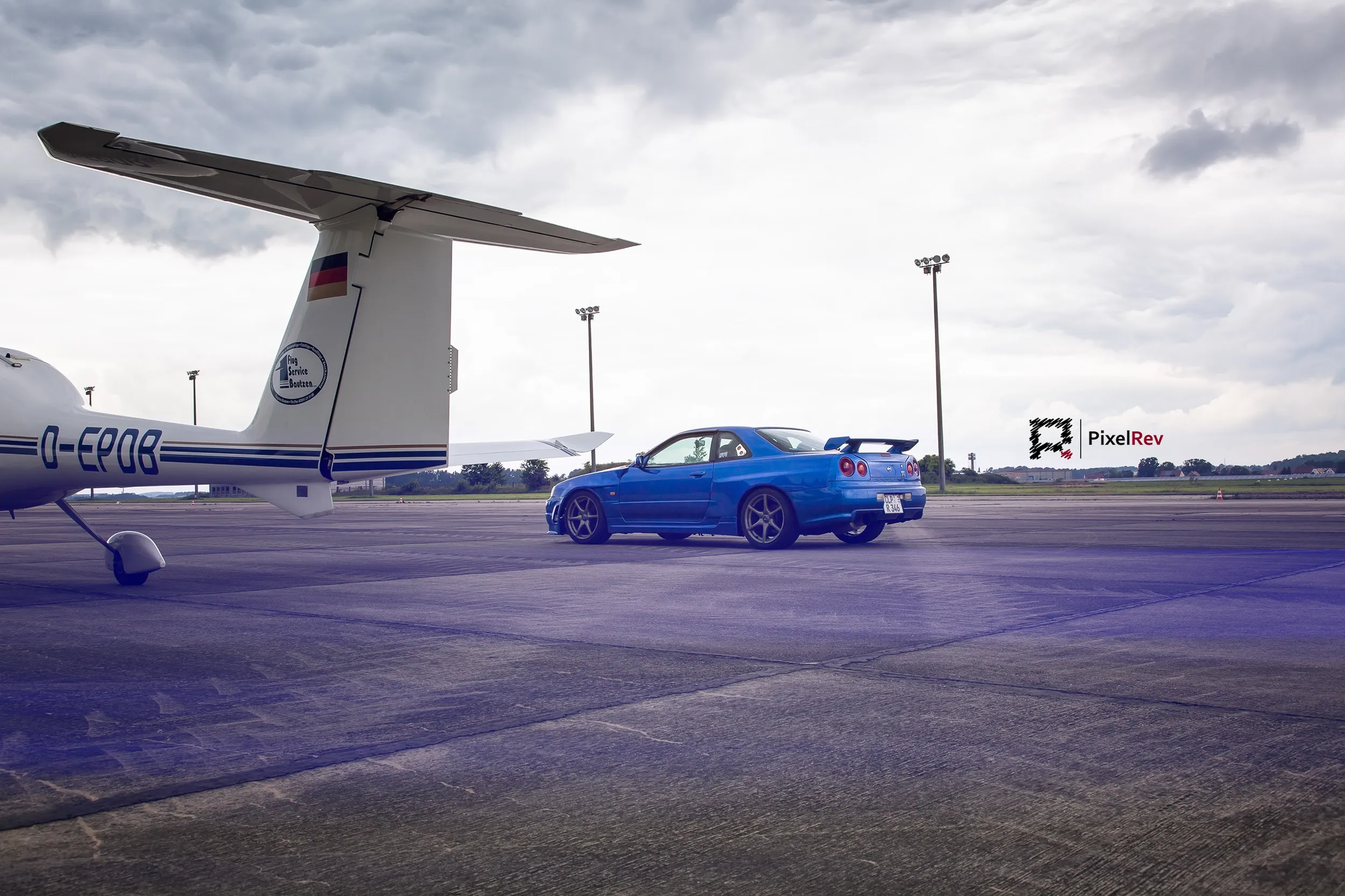 Nissan Skyline R34 GT-R auf dem Rollfeld, im Vordergrund ein Flugzeugflügel