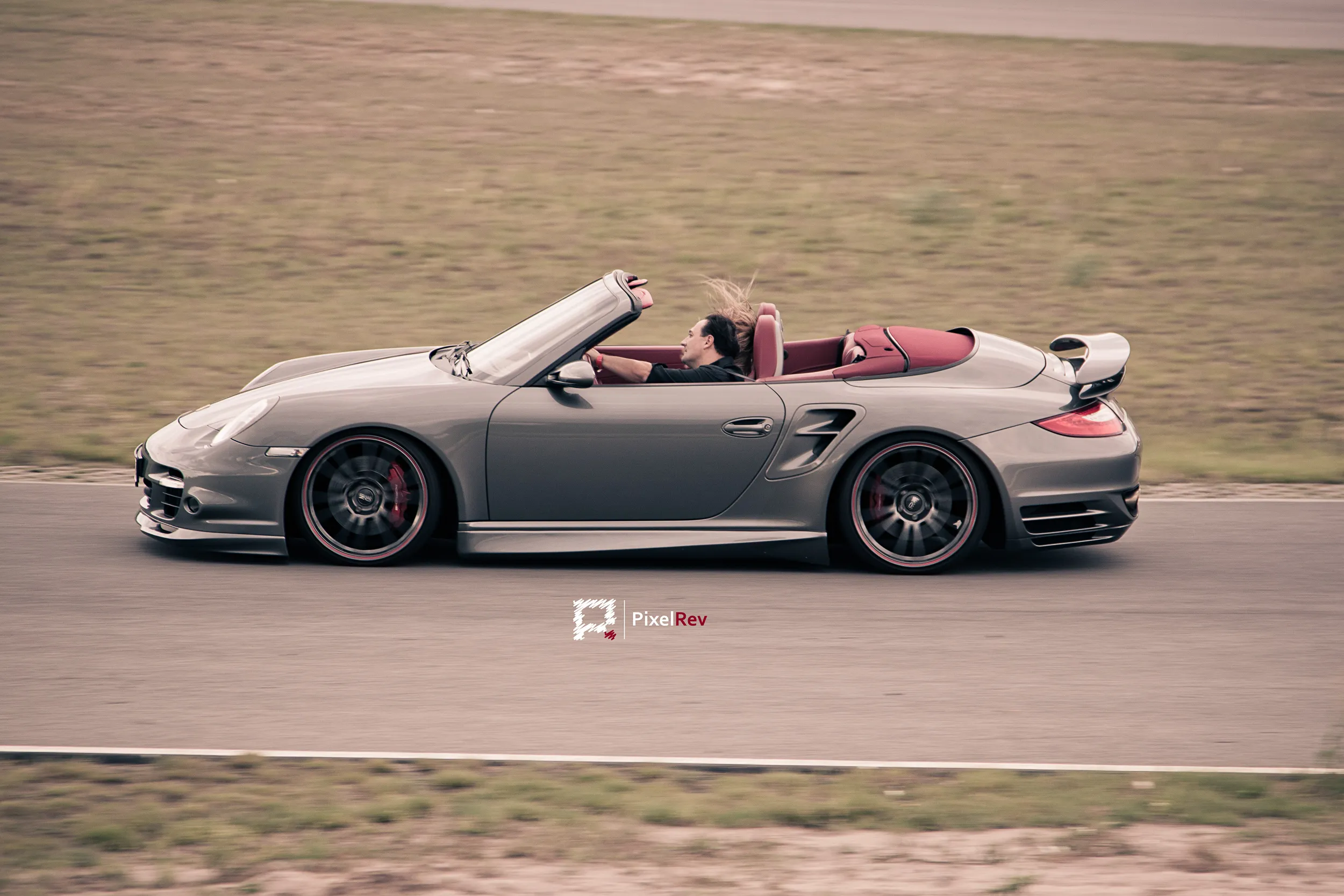 Grauer Porsche 911 Turbo Cabriolet im Mitzieher auf der Strecke bei der Sportwagen-Charity 2011
