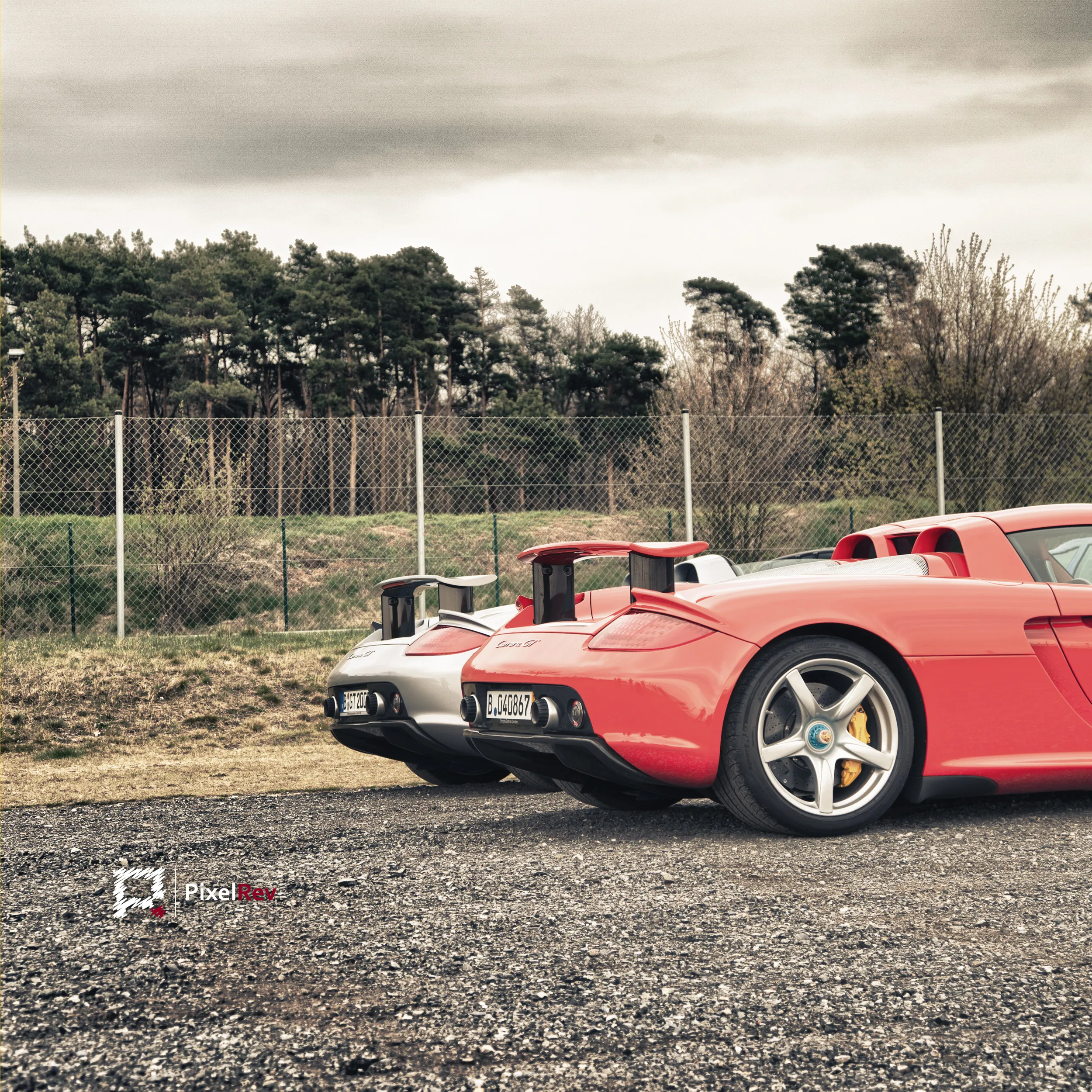 Roter und silberner Porsche Carrera GT nebeneinander auf Schotter