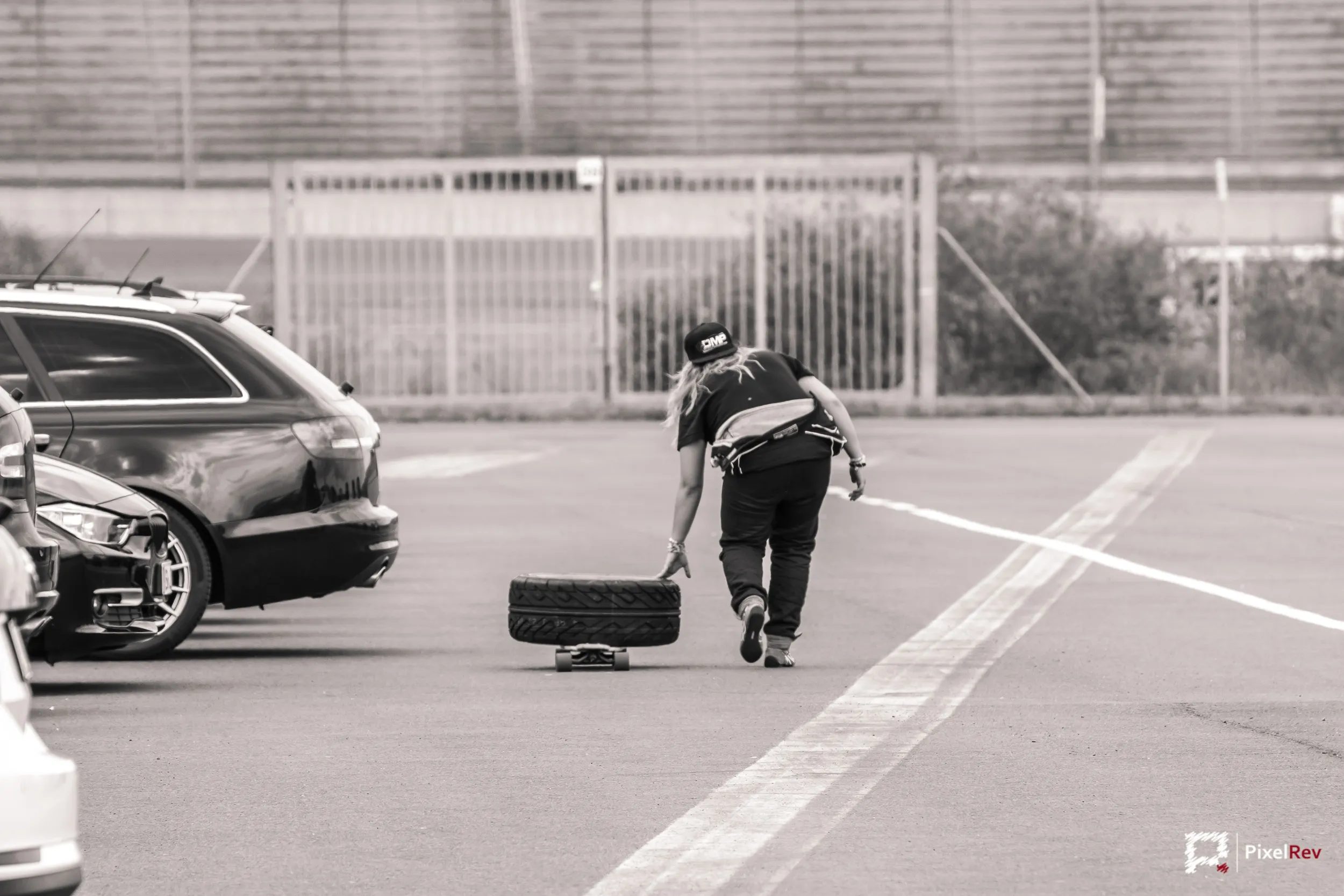 Person rollt einen Reifen über das Fahrerlager, Schwarz-Weiß
