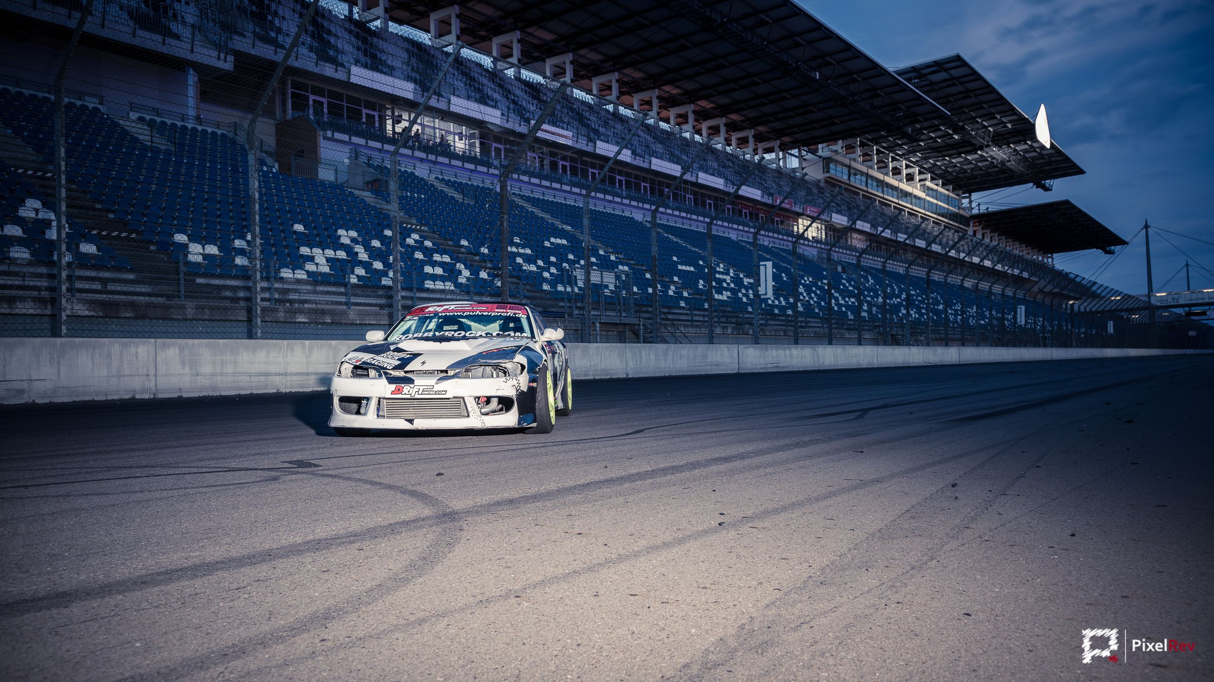 Driftfahrzeug von Robby Rock Racing vor der Tribüne am Lausitzring in der Abenddämmerung