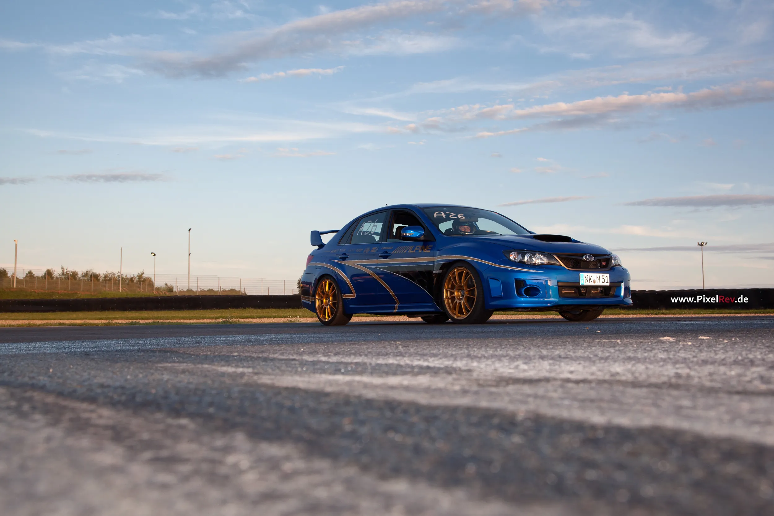 Blauer Subaru Impreza WRX STI mit goldenen Felgen auf dem Asphalt