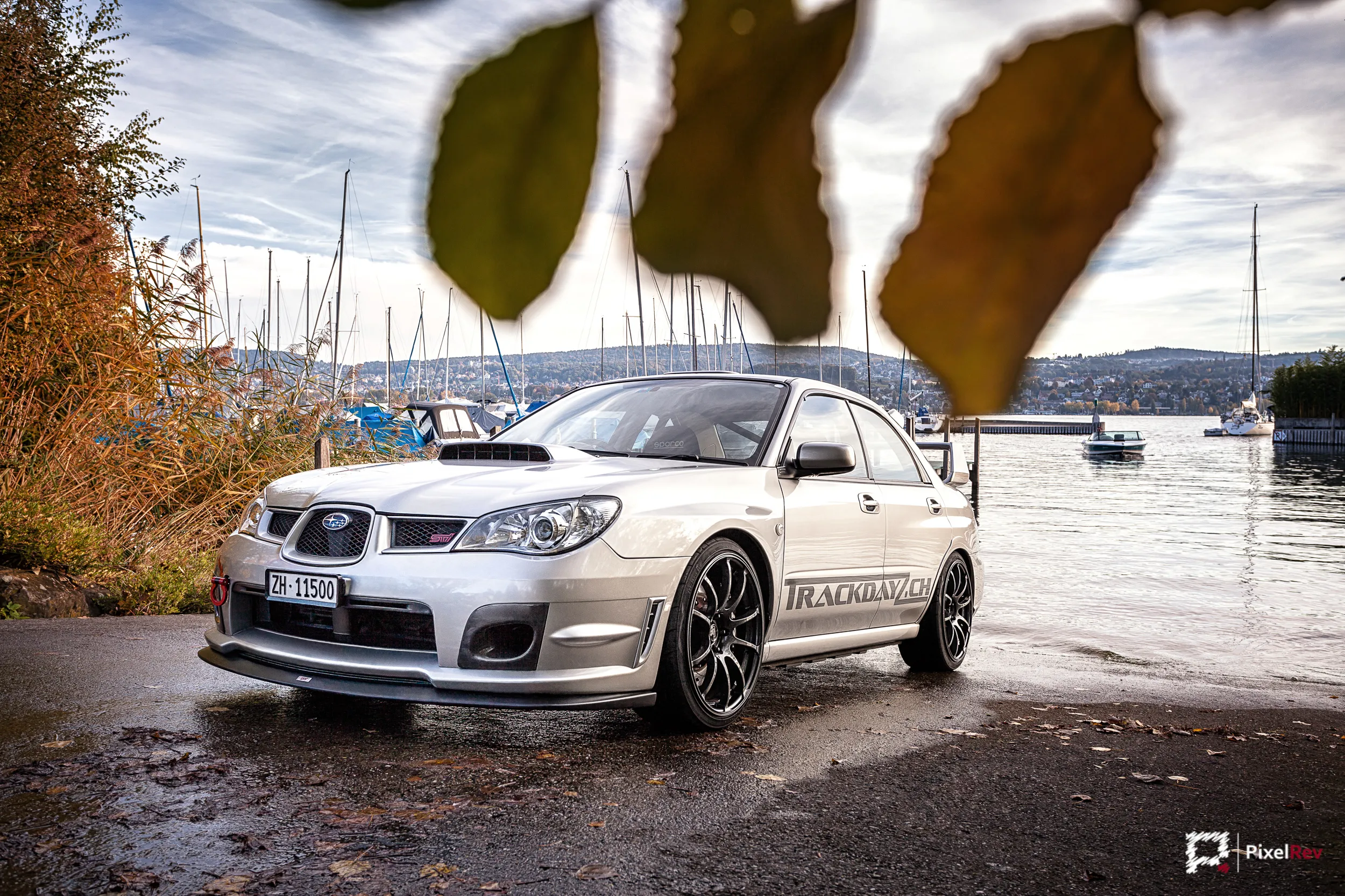 Silberner Subaru Impreza WRX STI am Ufer des Zürichsees, im Vordergrund Herbstlaub