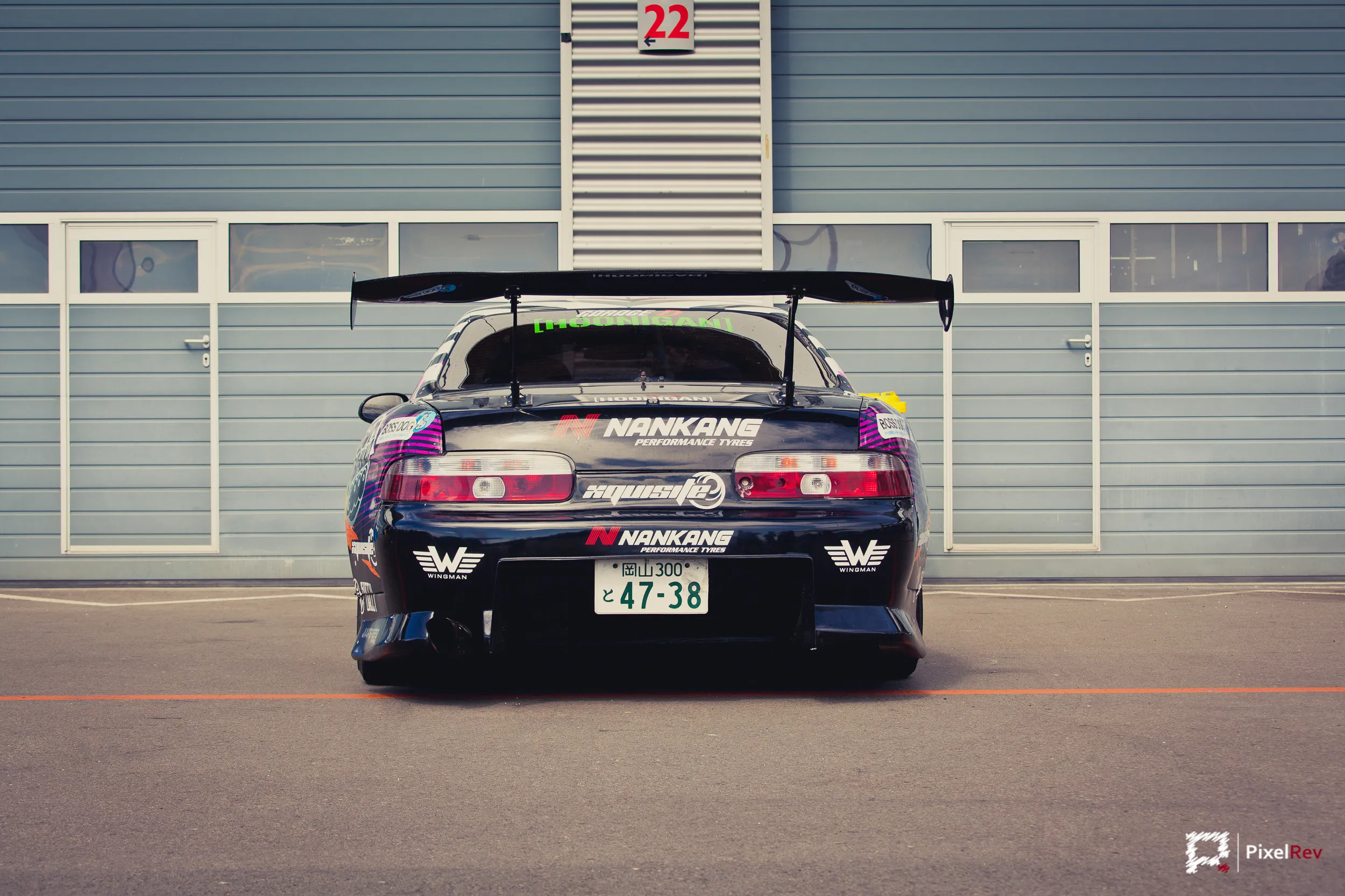 Heck eines Drift-Toyota Supra mit großem Heckflügel vor der Box