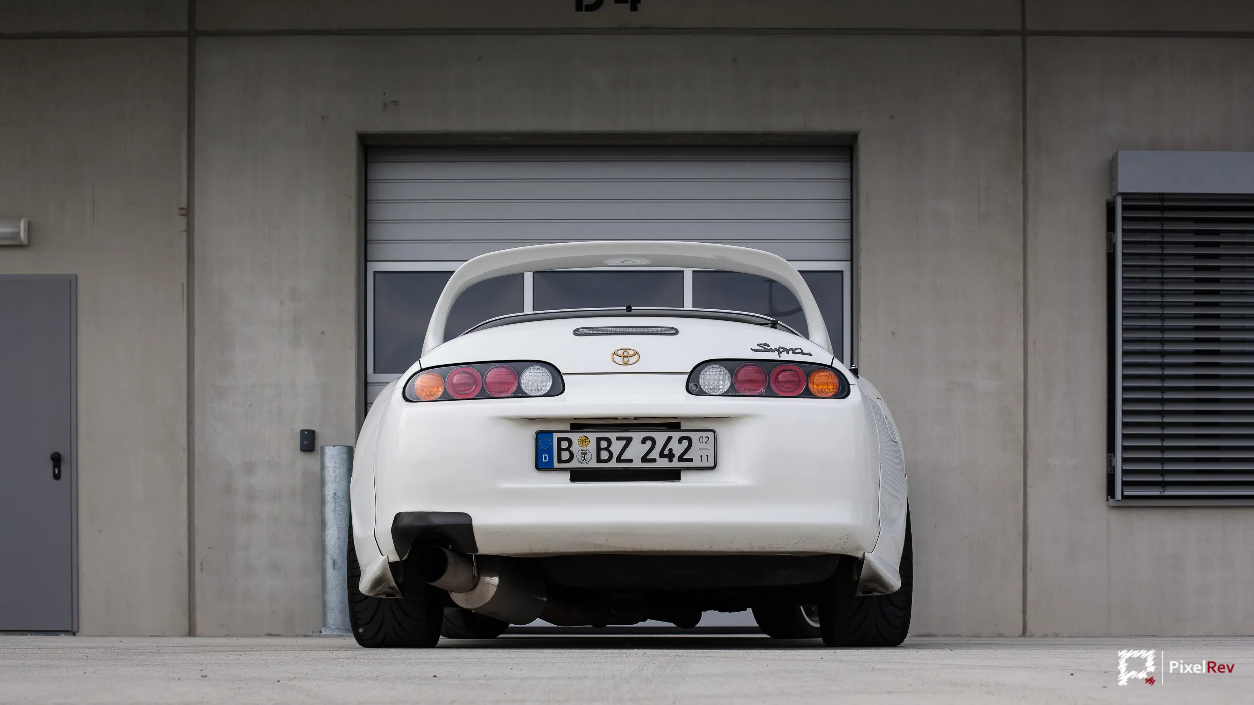 Heck des weißen Toyota Supra vor einem Rolltor