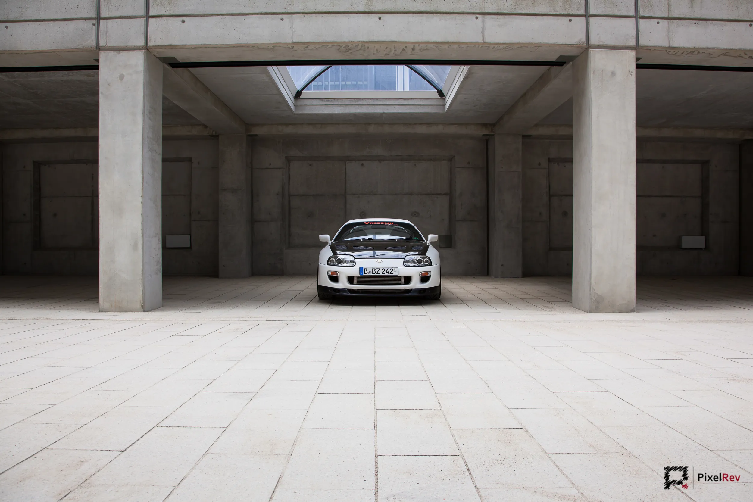 Weißer Toyota Supra frontal in einer großen Betonhalle