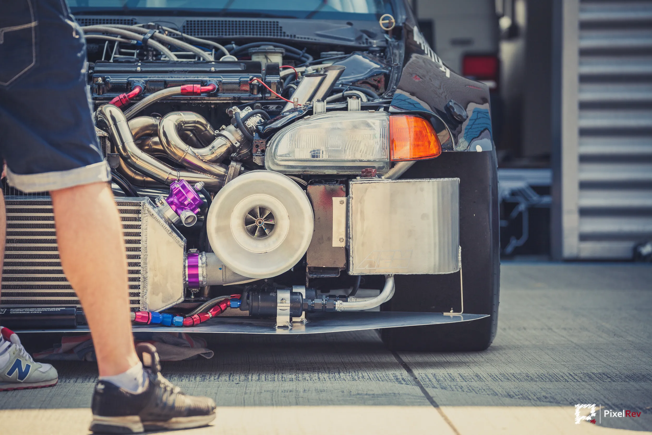 Offener Motorraum mit großem Turbolader, daneben die Beine eines Mechanikers